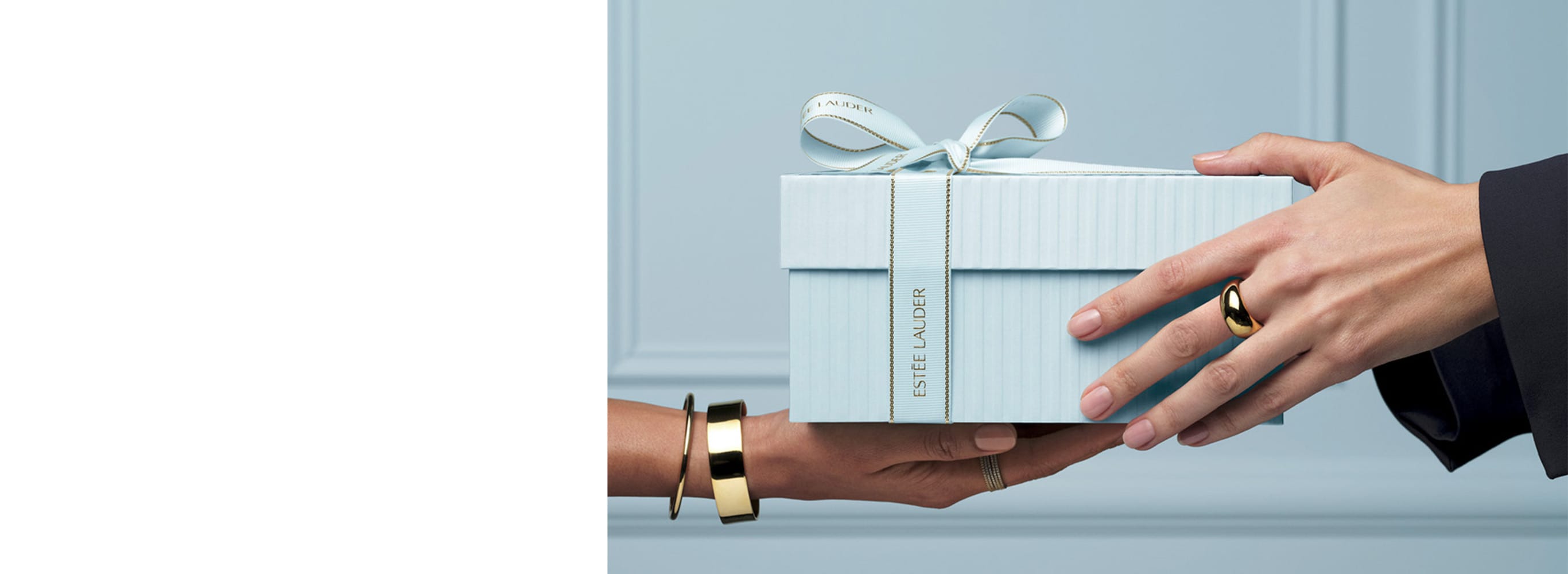 Image of someone handing over a Estee Lauder gift box to someone else