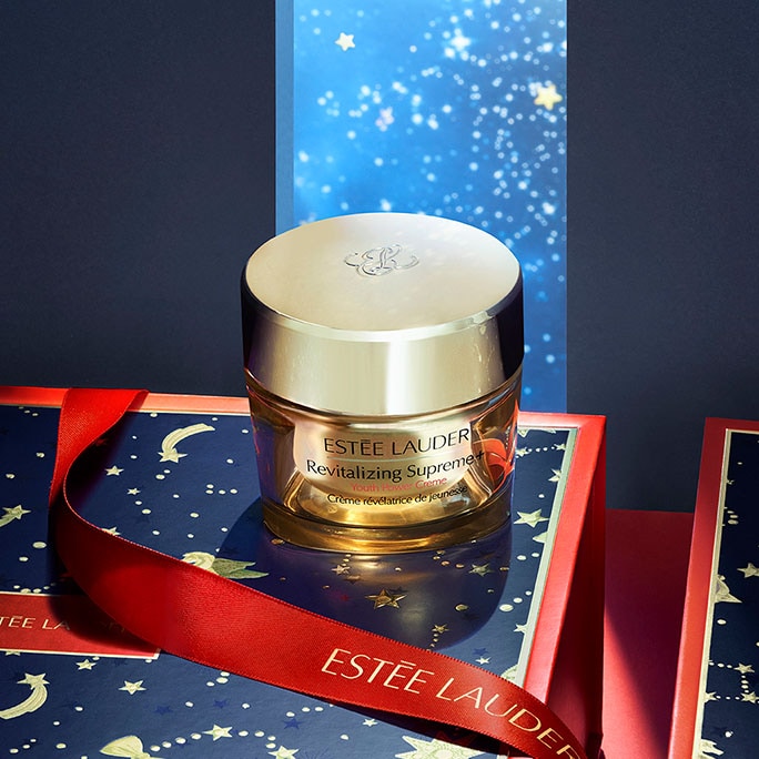 Estée Lauder Revitalizing Supreme moisturiser displayed in a red and navy-blue scene with a starry background