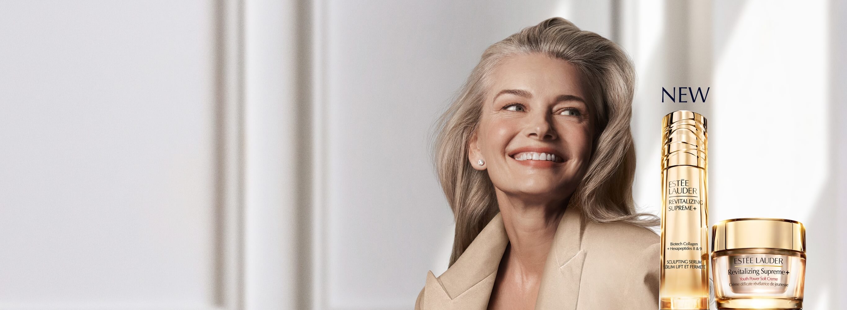 A selection of Estee Lauder Revitalizing Supreme+ products with a model on a light silver background