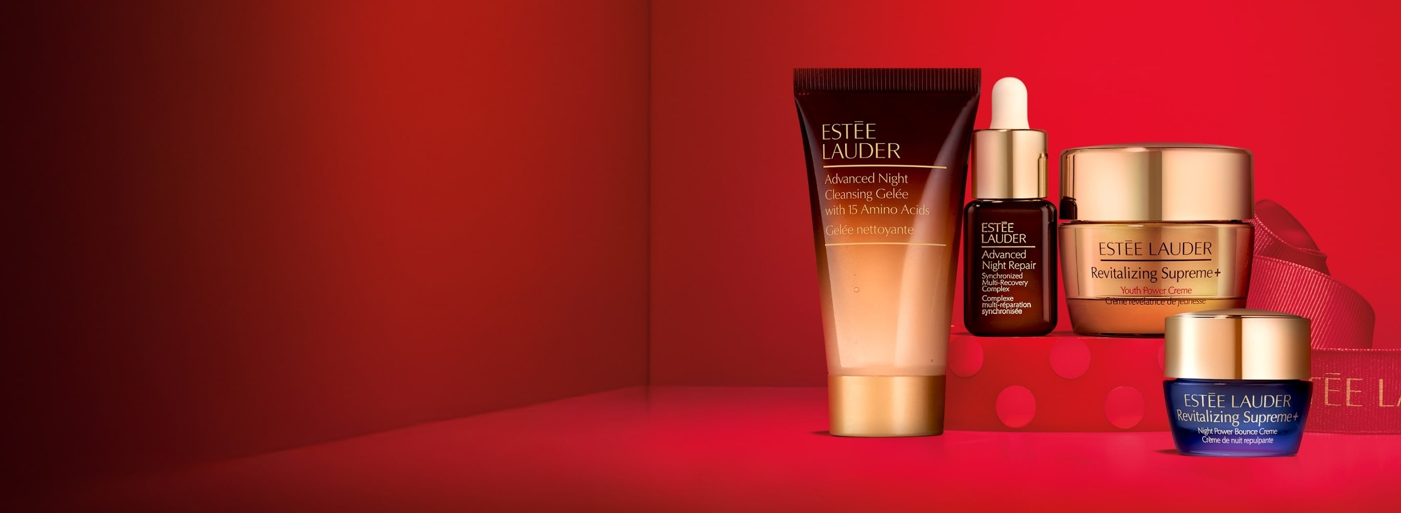 Estée Lauder products on a red background with gifting ribbon