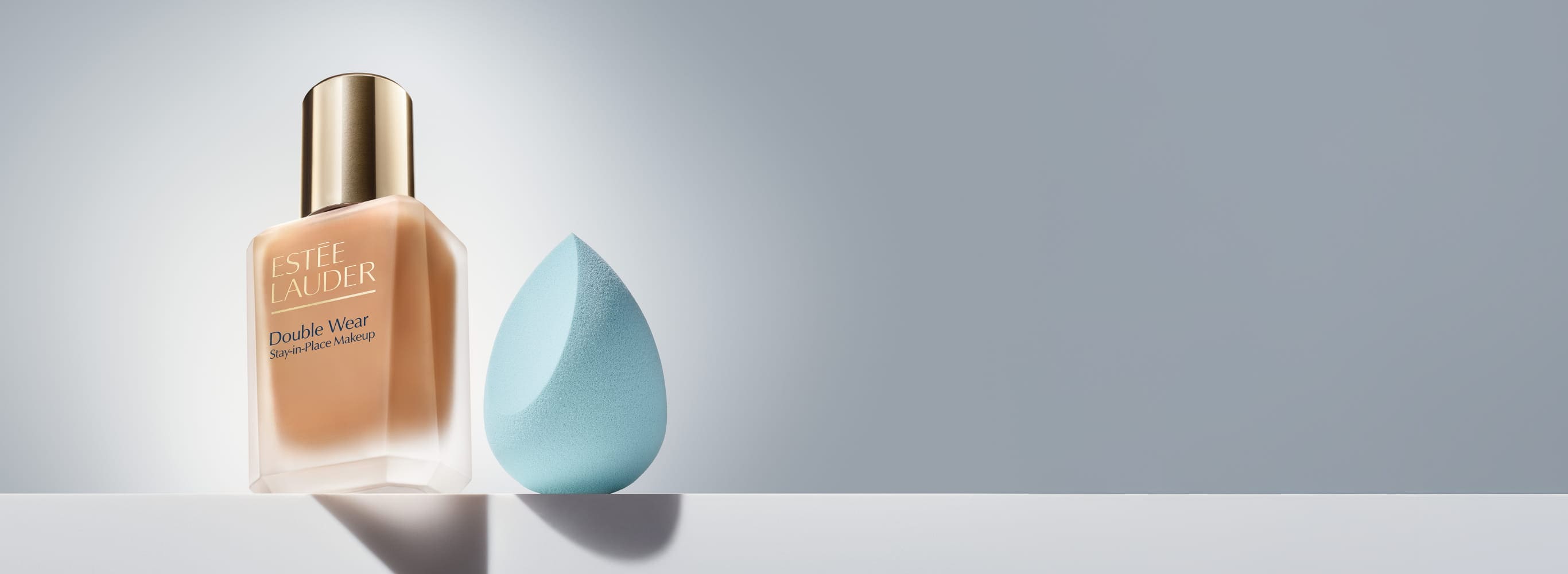 New Estee Lauder Double Wear and beauty sponge on a grey background