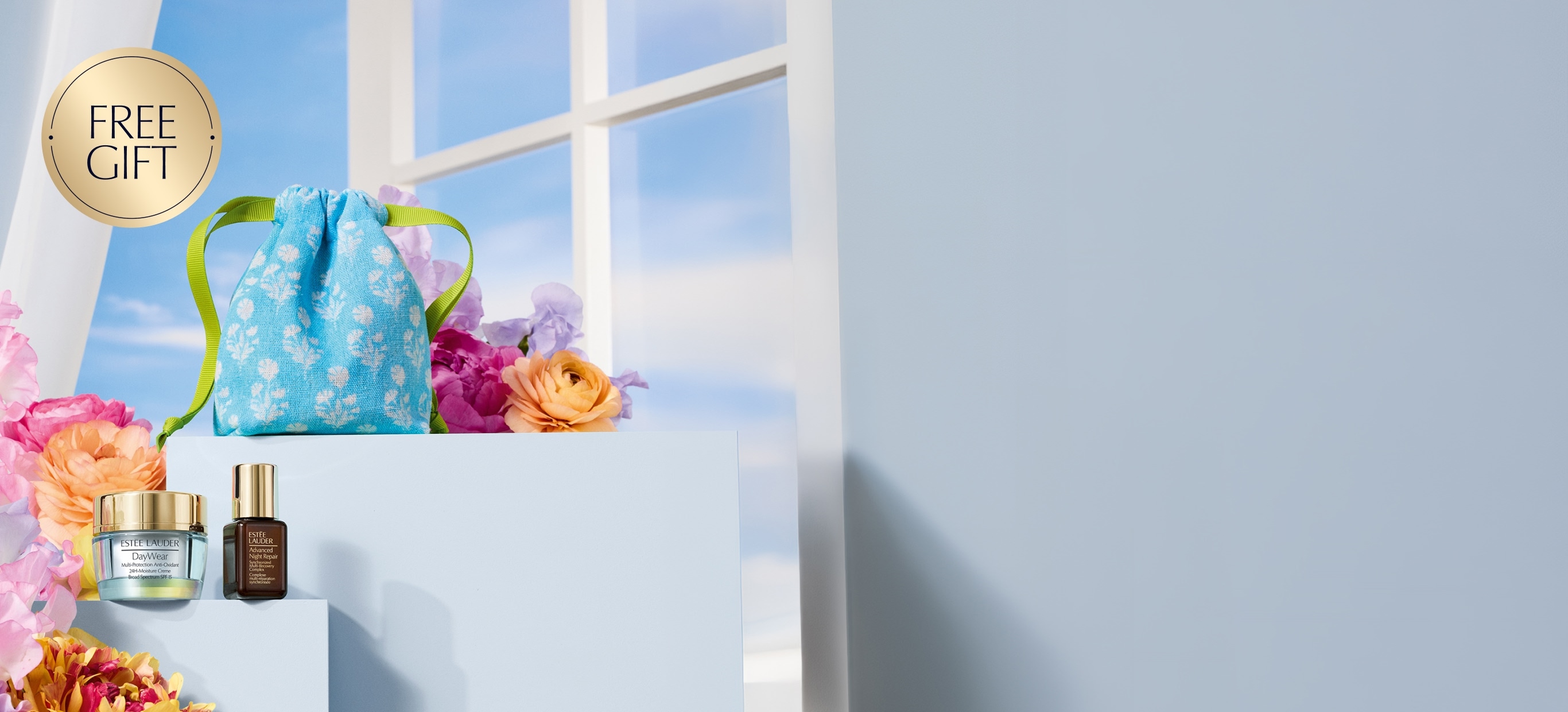 Estée Lauder products on a pale blue background with flowers
