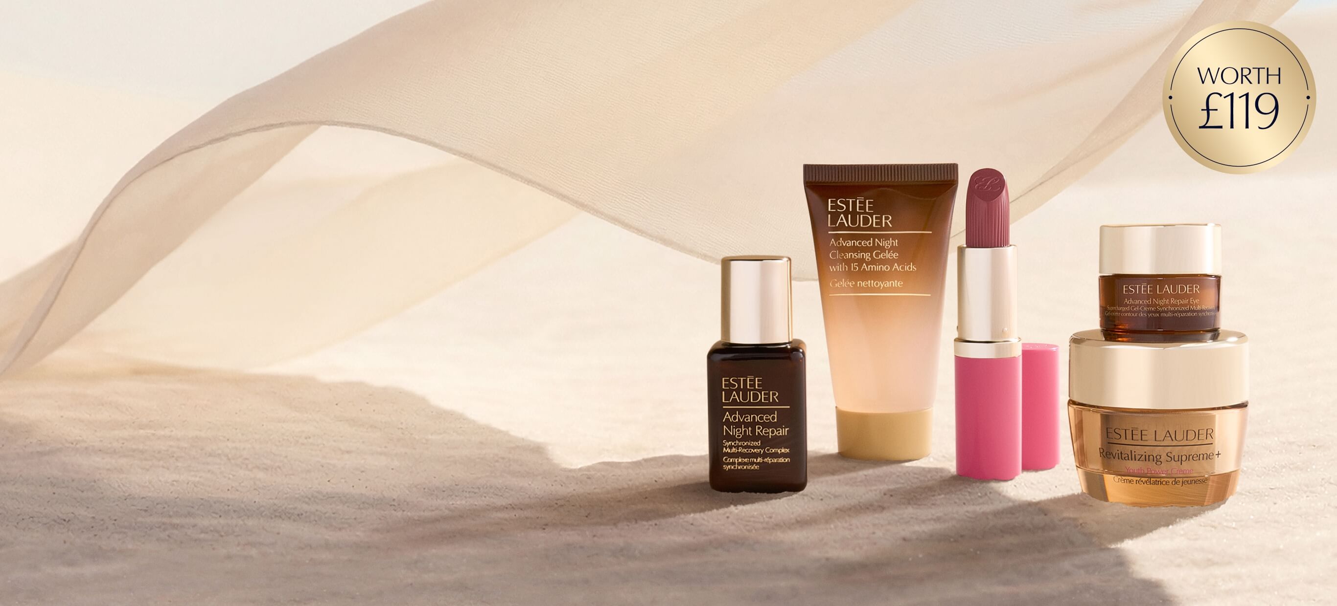 Estée Lauder products on a sand background