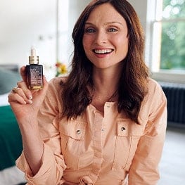 Sophie Ellis-Bextor smiling, holding a bottle of Advanced Night Repair Serum. 