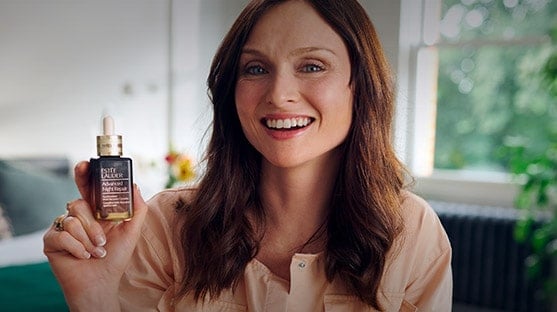 Sophie Ellis-Bextor smiling, holding a bottle of Advanced Night Repair Serum. 