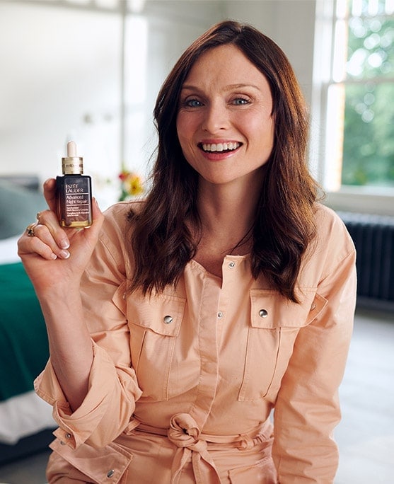 Sophie Ellis-Bextor smiling, holding a bottle of Advanced Night Repair Serum. 