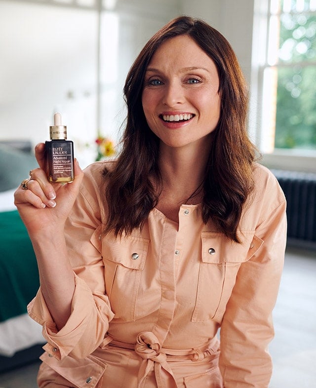 Sophie Ellis-Bextor smiling, holding a bottle of Advanced Night Repair Serum.