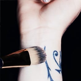 Double Wear Maximum Coverage Foundation for Face and Body SPF 15 being applied to a tattooed wrist, and the finished result of no tattoo visible once applied. 
