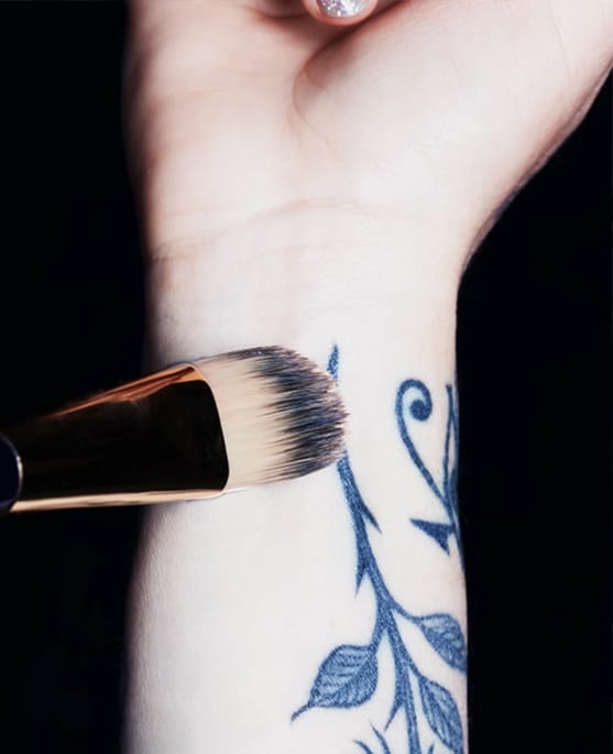 Double Wear Maximum Coverage Foundation for Face and Body SPF 15 being applied to a tattooed wrist, and the finished result of no tattoo visible once applied. 