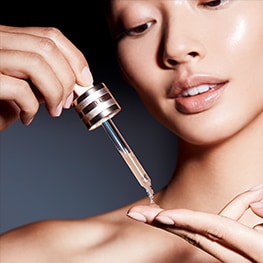 A model drops Advanced Night Repair Serum onto her fingers, ready to apply to the face. 