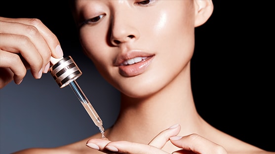 A model drops Advanced Night Repair Serum onto her fingers, ready to apply to the face. 
